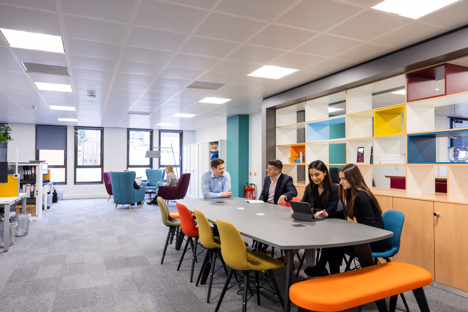 Group of men and women sat talking in an office