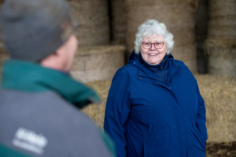 A member of our agriculture and estates team on a farm talking to a client and smiling