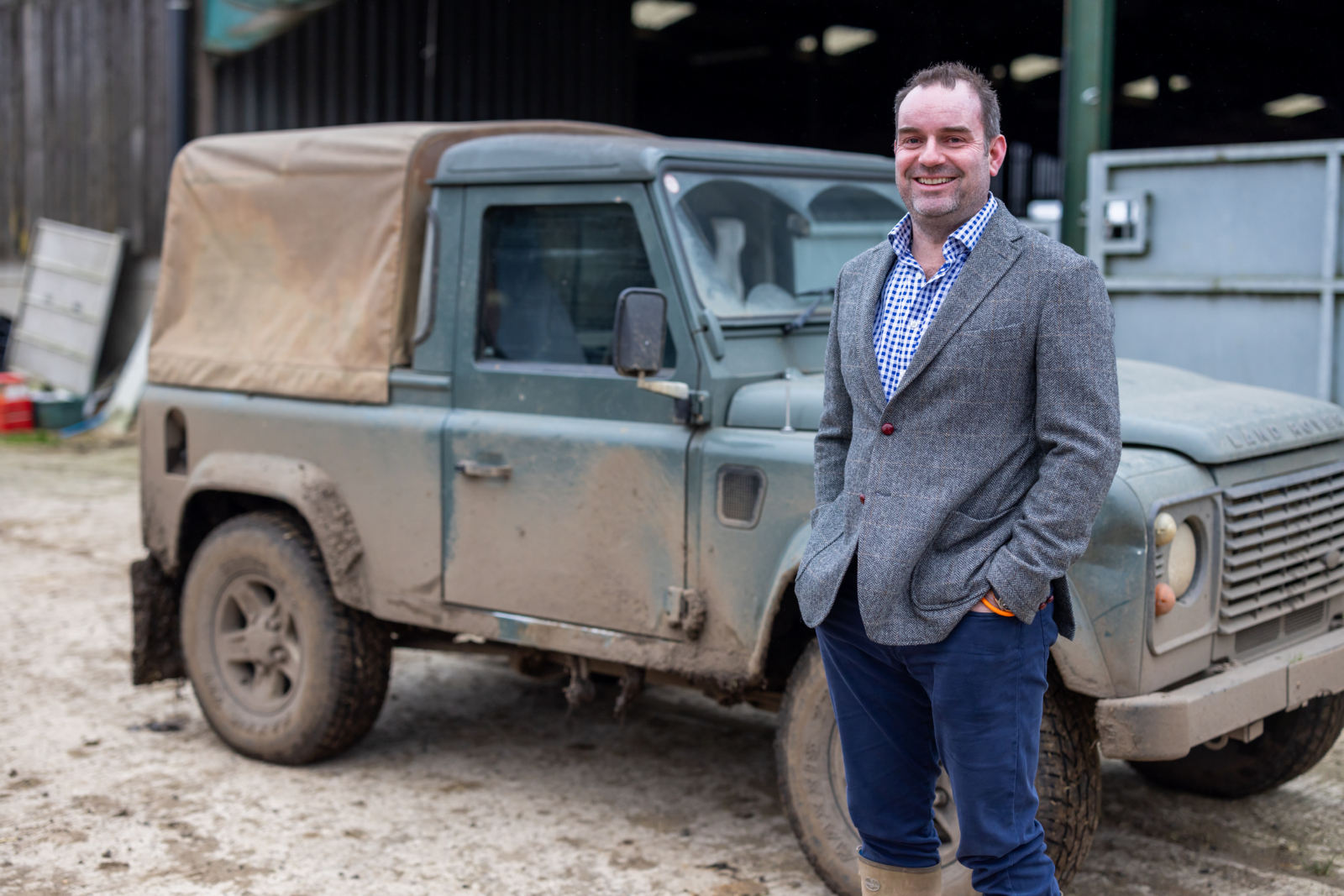 Lawyer on a landed estate farm standing in front of a land rover.