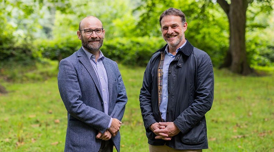 Two partners standing in a green field smiling