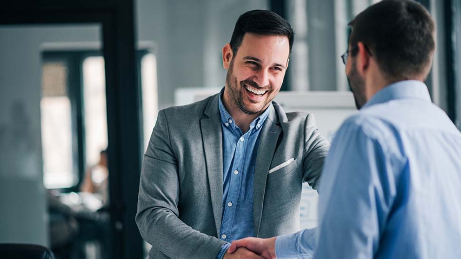 two men shaking hands and smiling