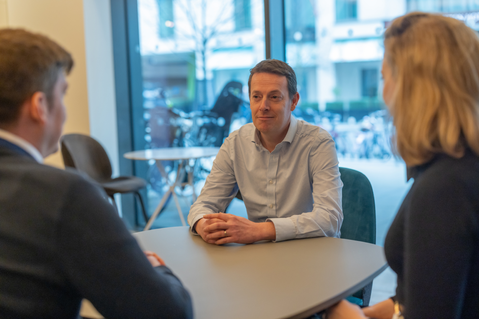 Solicitor talking to two clients sitting opposite to him on a table