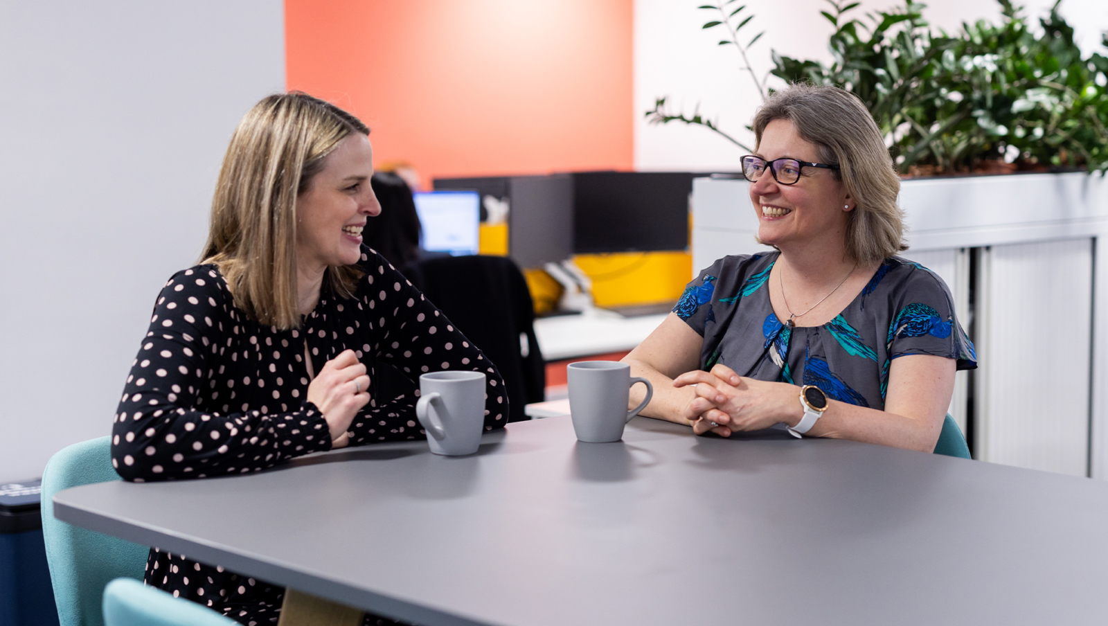 Two women chatting to each other with a cup of coffee in front of each of them