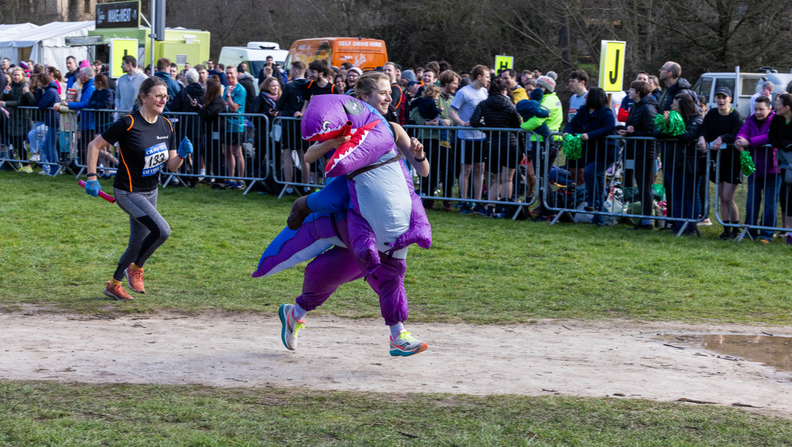 A relay race runner wearing a dinosaur costume
