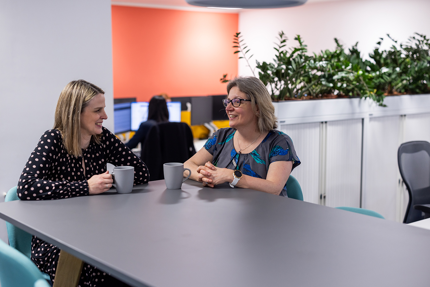 two people stood at a high table talking with mugs on the table