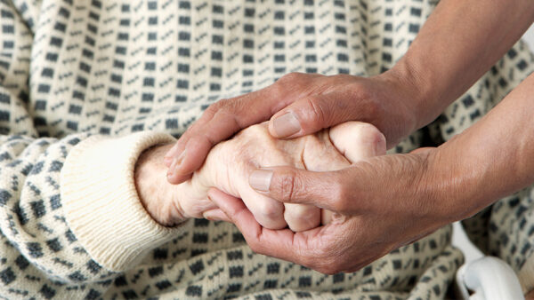Image of a vulnerable woman having her hand held by a carer