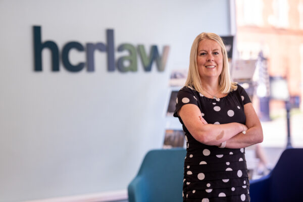 Charlotte Nutting standing by the HCR Law Logo