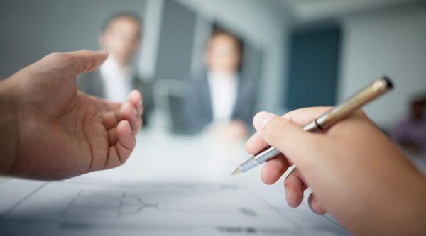 A picture of a hand holding a pen during a mediation meeting
