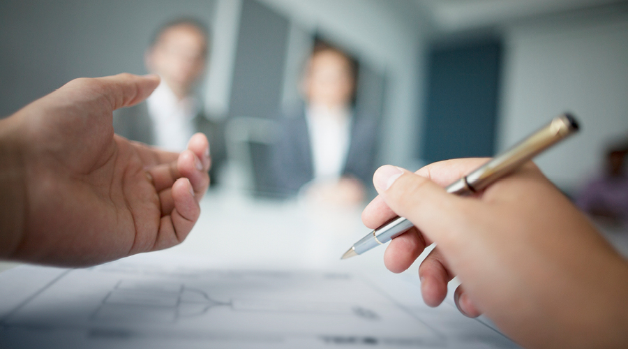 A picture of a hand holding a pen during a mediation meeting