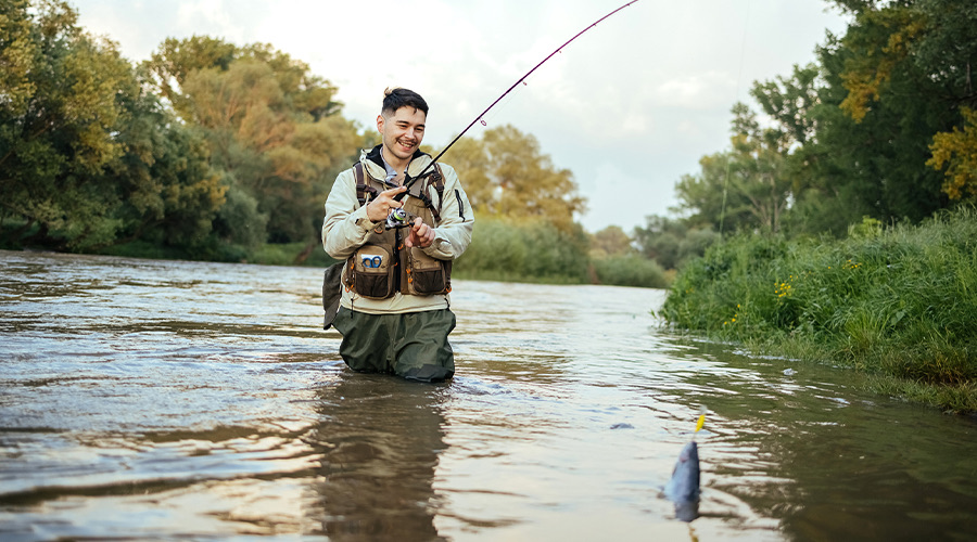 image of a a man stood in a river holding a fishing rod