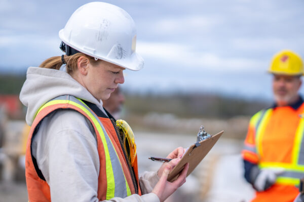 Female construction builder looking at clipboard