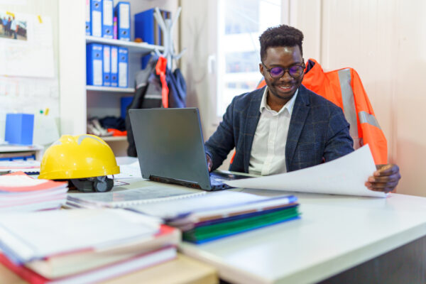 A man overseeing a construction project with contracts on his desk
