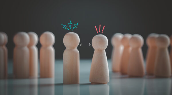 Two wooden figures facing each other with animated symbols—lightning bolts and exclamation marks—indicating conflict