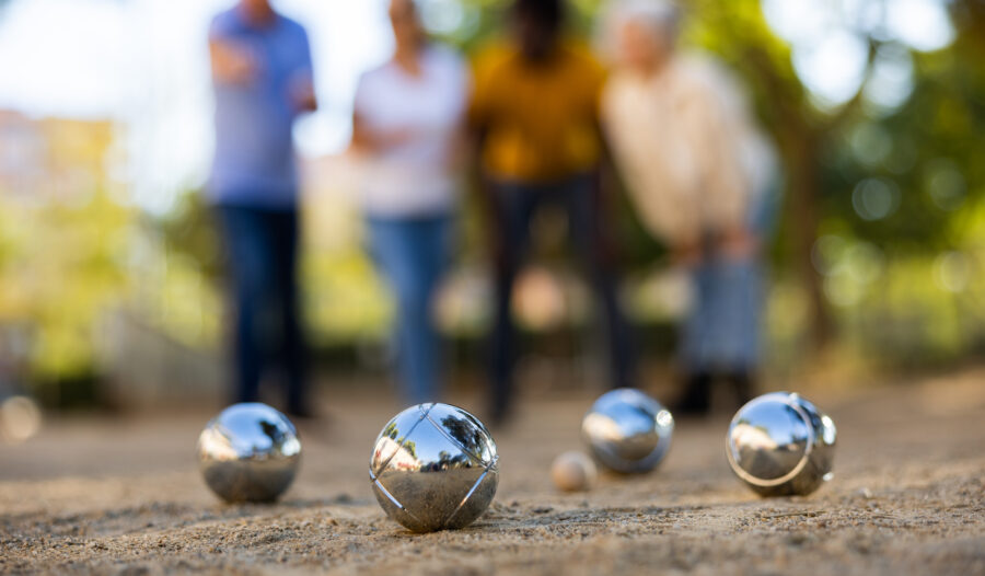 A game of petanque (also known as boules) being played outside in the sun