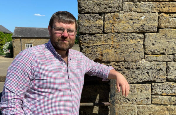 Hugh Powell leaning against a brick wall