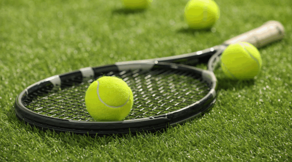 A tennis racket and balls on a grass court