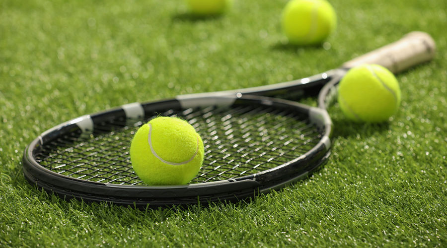 A tennis racket and balls on a grass court