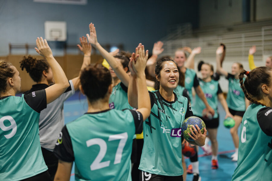 A group of multi-ethnic handball players greet each other after training
