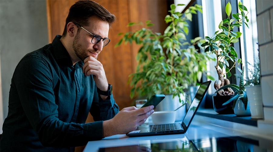 Male looking at his phone and laptop