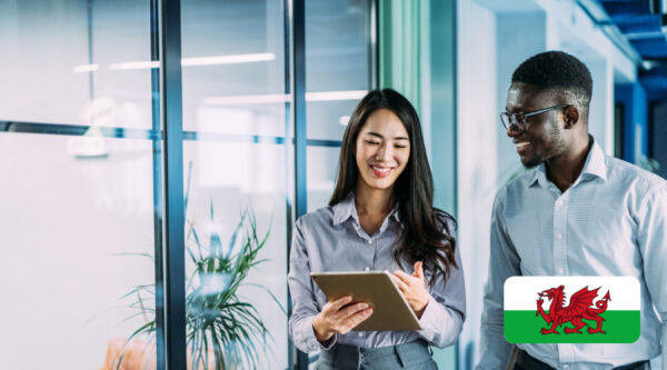 Two business people walking with an ipad and a Welsh Flag is on the image