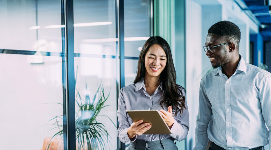 Two business people walking and talking with an ipad