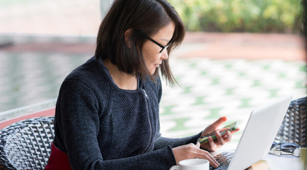 female looking at phone and laptop