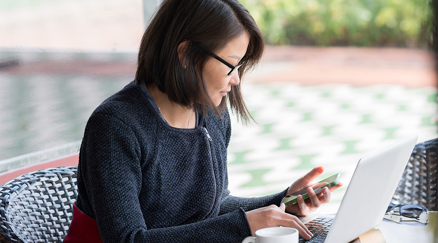 female looking at phone and laptop