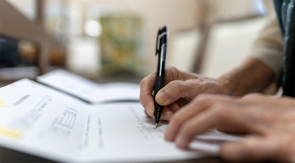 person writing on a paper with pen