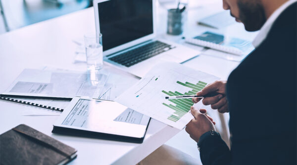 A man on a computer checking graphs for growth