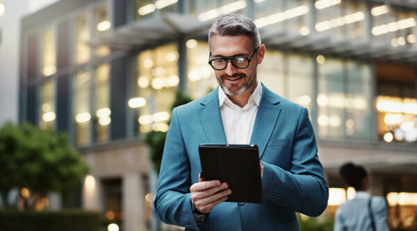 Business person holding a mobile tablet in front of a company