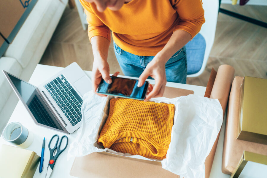 A woman taking a photo of a jumper to sell online