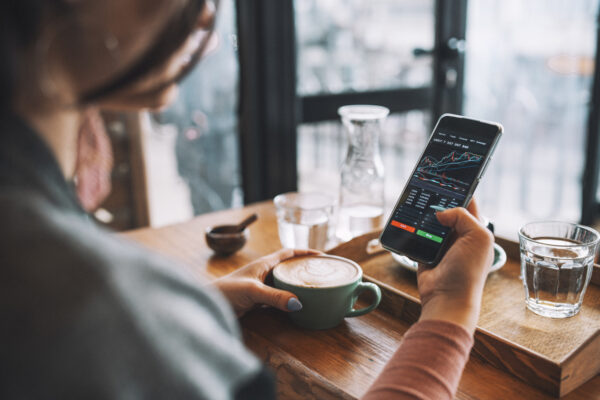 Woman in a cafe looking at data on phone, with coffee in front of her