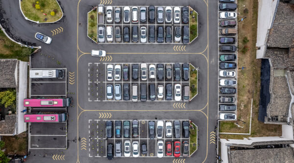 Top-down view of a managed car park with designated spaces, directional markings, and parked cars, representing controlled parking and enforcement conditions.