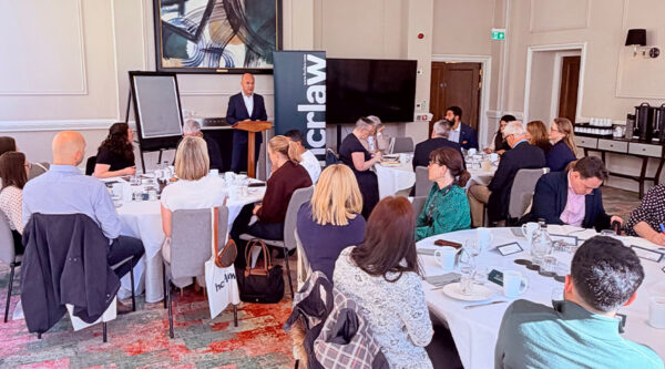 Speaker presenting at an HCR Law roundtable event, with attendees seated at tables discussing leadership challenges and opportunities in in-house legal teams.