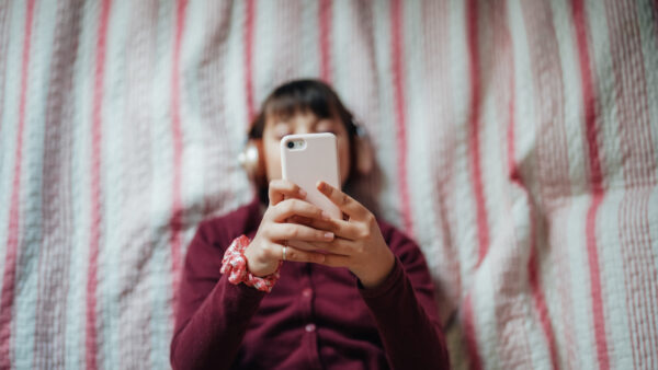 Girl in bed enjoying a good music from smartphone app