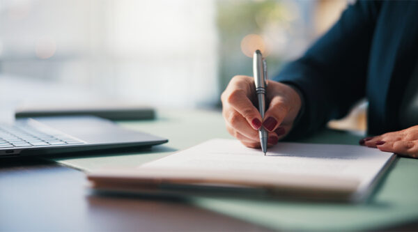 A hand signing a document