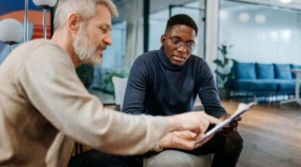 Two professionals reviewing contract documents together in an office, discussing amendments and updates to commercial agreements.