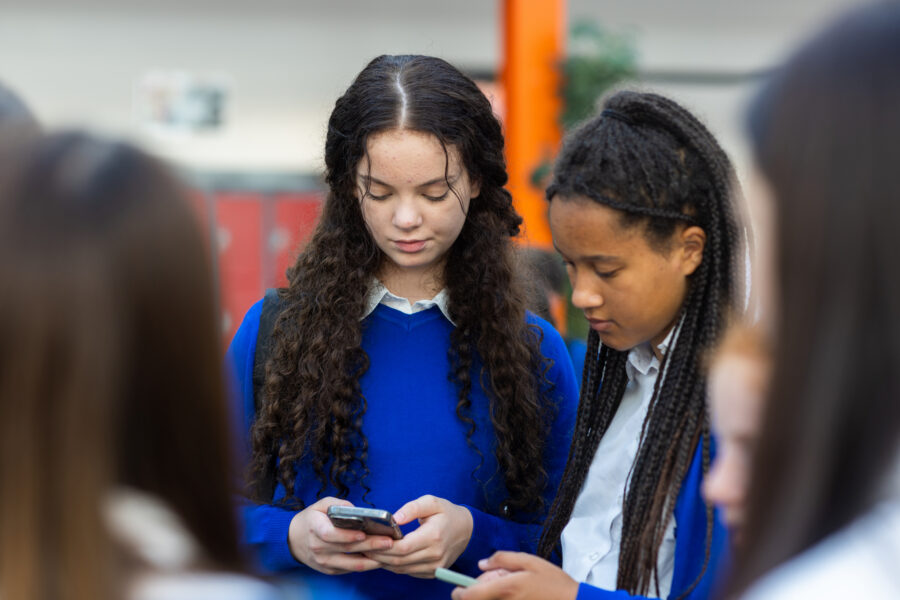 Child using a smartphone with social media icons, illustrating online safety and proposed restrictions on under-16s’ social media use.