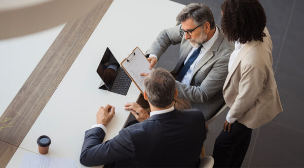 Three professionals reviewing a contract together at a meeting table