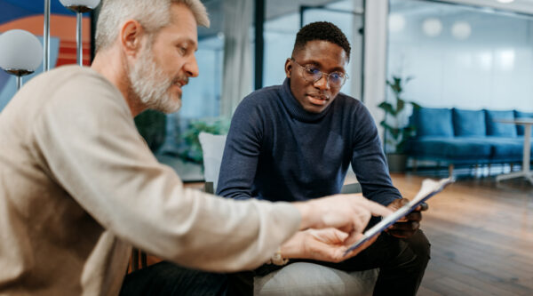 Two colleagues reviewing a document together during a meeting about commercial contract clauses.