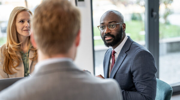 Three professionals discussing a case during a meeting in a bright office.
