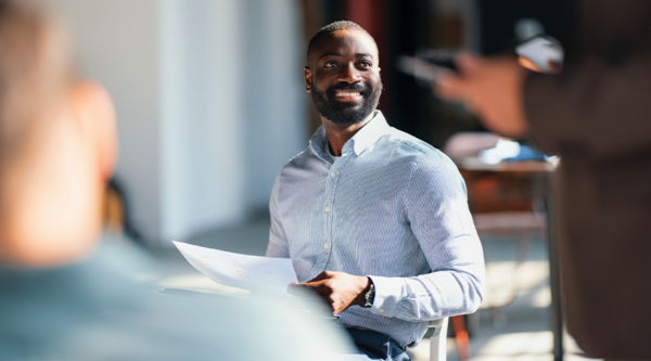 Business professional holding documents during a meeting with colleagues.