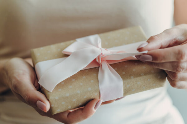 Close-up of hands holding a wrapped gift with a white ribbon, symbolising gifting and inheritance tax planning.
