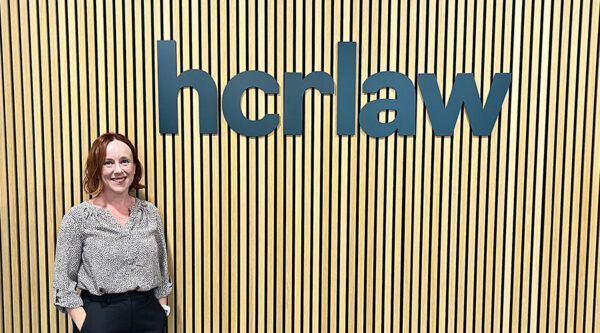 Kylie Cooper standing in front of an HCR Law sign at the firm’s office.