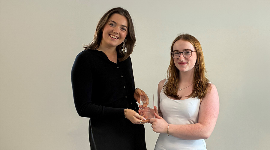 Two people holding a glass HCR award against a plain background.