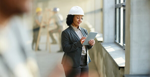 Property professional wearing a hard hat and writing on a clipboard