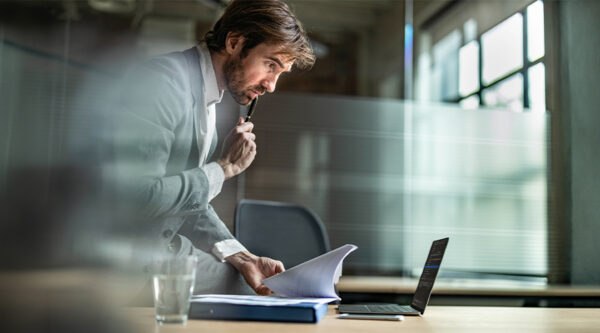 Business professional reviewing financial documents beside a laptop in a modern office, illustrating potential LLP liabilities.