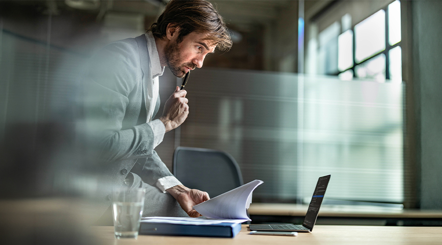 Business professional reviewing financial documents beside a laptop in a modern office, illustrating potential LLP liabilities.