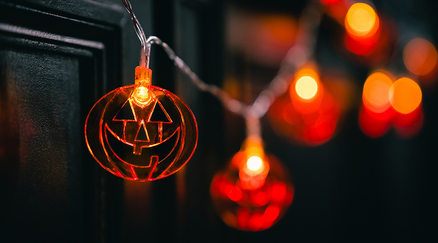 Orange pumpkin-shaped Halloween lights glowing against a dark background.