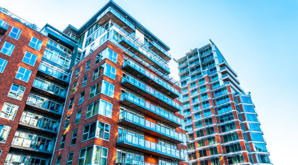 Modern high-rise apartment buildings with red-brick façades, glass balconies and large windows.